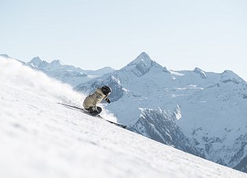 Skifahrer auf verschneiter Piste mit Kitzsteinhorn im Hintergrund